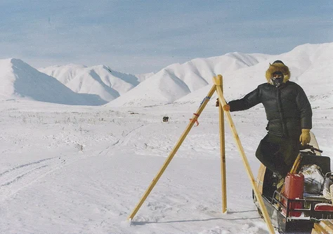 Man and snow machine on Iditarod trail in winter.